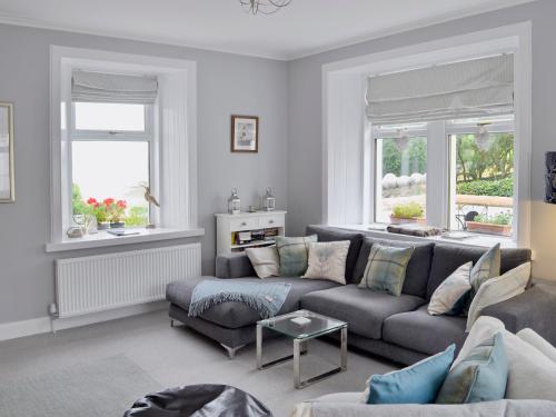 a living room with a couch and two windows at Balcary Mews Cottage in Auchencairn