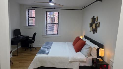 a bedroom with a bed and a desk and two windows at Quiet cheerful condo in the heart of OTR! in Cincinnati