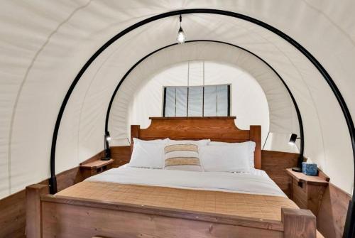 ein Schlafzimmer mit einem großen Bett in einem Zelt in der Unterkunft Unique Conestoga Glamping Wagon with King Bed & Private Bath | Bonners Ferry, Idaho Retreat in Bonners Ferry
