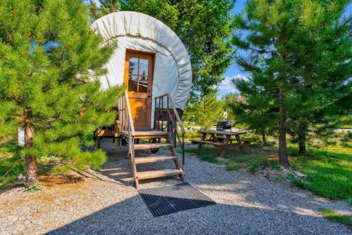 ein winziges Baumhaus im Wald mit einer Leiter in der Unterkunft Unique Conestoga Glamping Wagon with King Bed & Private Bath | Bonners Ferry, Idaho Retreat in Bonners Ferry