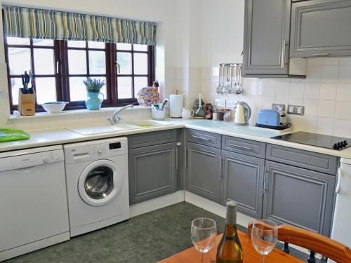a kitchen with a washing machine and a table with wine glasses at Spinnakers in Falmouth