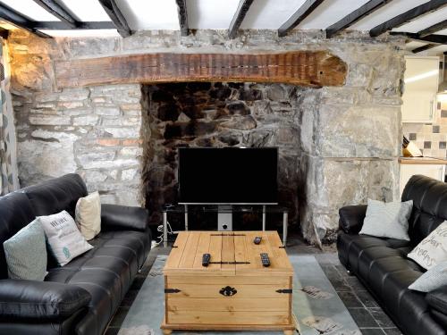 a living room with leather couches and a flat screen tv at Pendref in Trawsfynydd