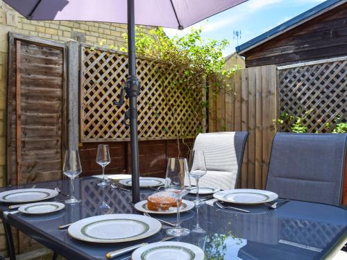 einen Tisch mit Teller mit Lebensmitteln und einem Regenschirm in der Unterkunft Bow Cottage in Bourton on the Water