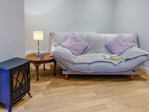 a couch in a living room with purple pillows at The Cottage-Uk32854 in Alltwen