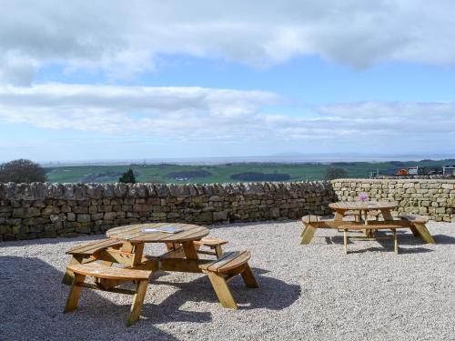 two picnic tables in front of a stone wall at Lakeland View in Scotforth