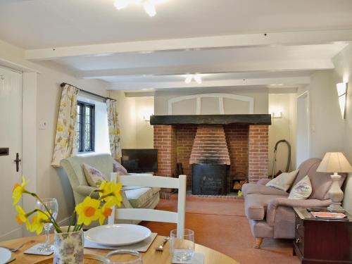 a living room with a brick fireplace and a table at Violet Cottage in Catfield