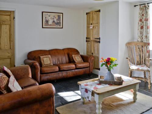 a living room with a leather couch and a coffee table at Gewans Farm Cottage in St Austell