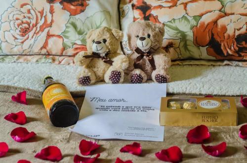 Zwei Teddybären sitzen auf einem Sofa mit roten Rosen. in der Unterkunft Chalé Quinta São Miguel 01 - Econômico in Santo Antônio do Pinhal