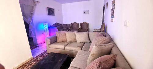 un salon avec un canapé dans une pièce avec des lumières violettes dans l'établissement شقه مفروشه بالشروق بالقرب من مدينتى للعائلات و الاسر فقط, à Madīnat aţ Ţalāʼi‘