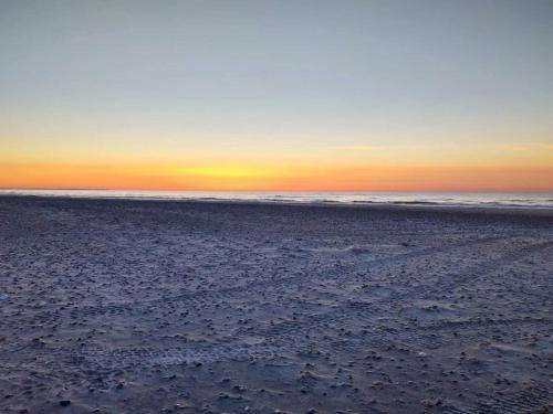 a beach with the sun setting over the ocean at 6 person holiday home in Fjerritslev in Fjerritslev