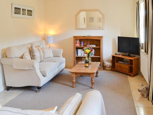 a living room with a white couch and a tv at Lily Broad Cottage in Burgh Saint Margaret