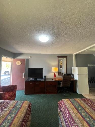 Una habitación de hotel con dos camas y un escritorio con televisión. en Western Capri Motel, en Tulsa