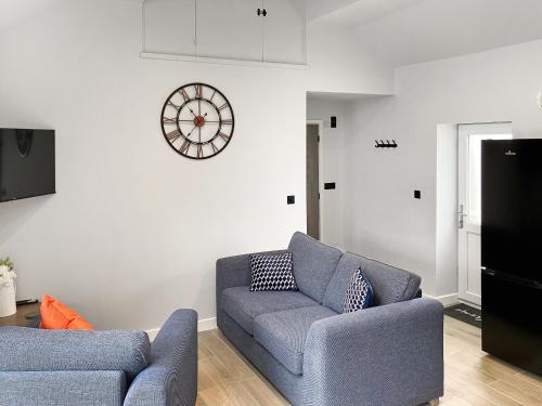 un salon avec un canapé et une horloge au mur dans l'établissement Llaethdy Arfryn, à Maenclochog