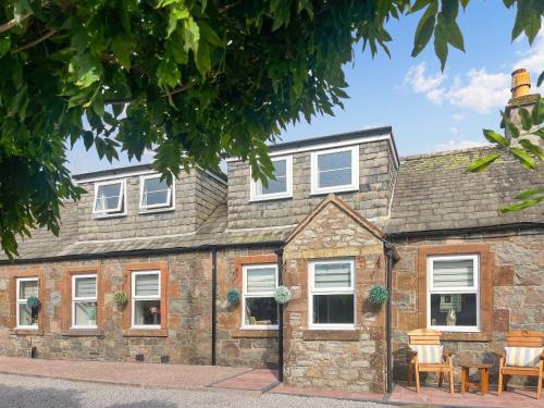 une vieille maison en pierre avec des fenêtres blanches dans l'établissement Holly Cottage, à Palnackie