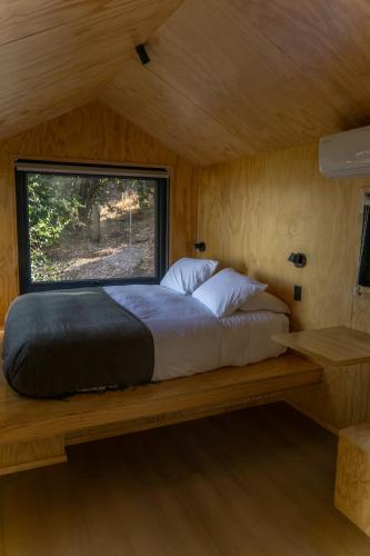 a bed in a room with a window at Cabins entre bosques y viñedos con vistas al valle - Tucu cabins in Maipo
