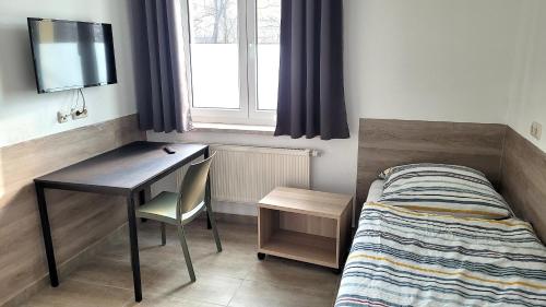a small bedroom with a bed and a desk and a window at Monteurhotel Leuna in Leuna