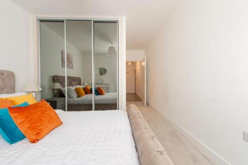 een slaapkamer met een wit bed en een oranje kussen bij Casa Di Dolce Two Bedroom Apartment with Balcony in Maidstone