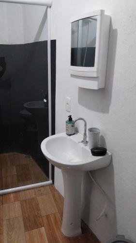 a bathroom with a white sink and a microwave at Casa para alugar in Paraty