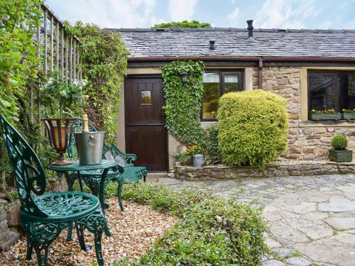 eine Terrasse mit Tisch und Stühlen vor einem Haus in der Unterkunft Garden Cottage in Sabden