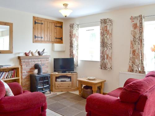 een woonkamer met twee rode stoelen en een televisie bij The Milking Parlour - 18436 in Bempton