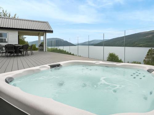 a hot tub on a deck with a view of the water at Chapelburn in Lawers