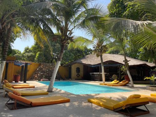 einen Pool mit gelben Liegestühlen und Palmen in der Unterkunft La Tour Rouge in M'bour