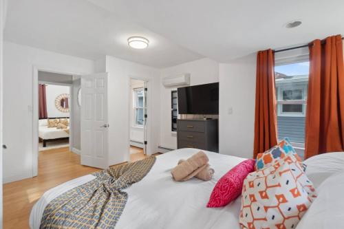 ein Schlafzimmer mit einem weißen Bett mit Kissen darauf in der Unterkunft Modern 5BR Corporate Stay 10 Mins to NYC + Parking in Guttenberg