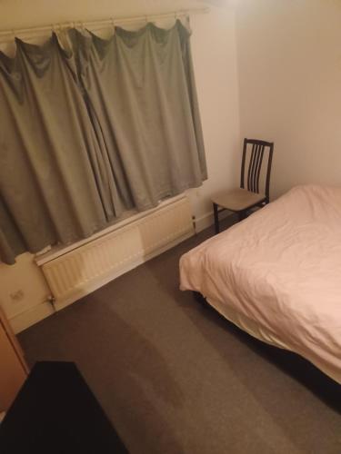 a bedroom with a bed and a window with a chair at Cozy King Room with Shared Kitchen & Bathroom in Lewisham