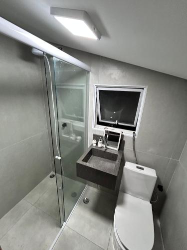Apartamento Charmoso com Mezanino em Juquehy في ساو سيباستياو: حمام مع مرحاض ومغسلة وتلفزيون
