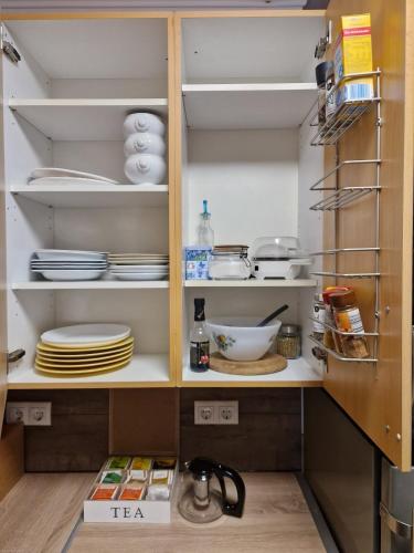 a cupboard filled with plates and dishes in a kitchen at quiet apartment 2 in Rüsselsheim