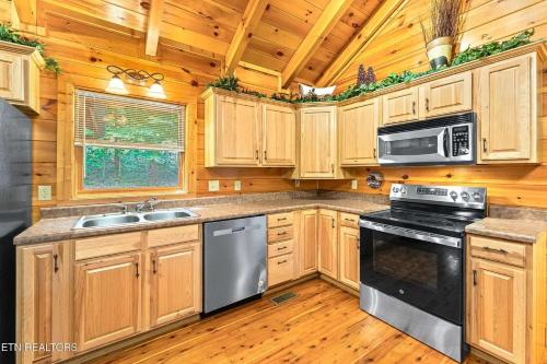 a kitchen with wooden cabinets and a stove top oven at Along the Trail Cabin with Hot Tub Pool Pond Game Room in Wear Valley