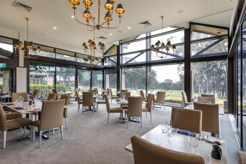 a restaurant with tables and chairs and large windows at Chateau Elan At The Vintage in Pokolbin
