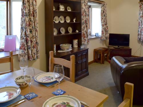 ein Wohnzimmer mit einem Tisch mit Tellern und Weingläsern in der Unterkunft Hazel Cottage in Ambleside