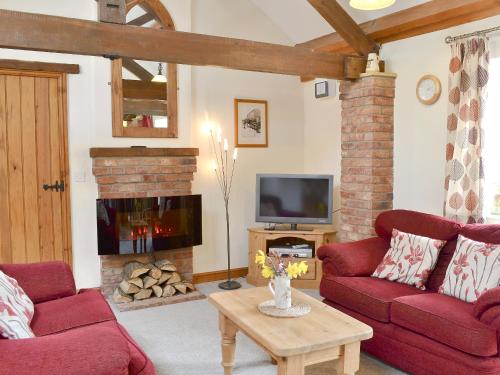 een woonkamer met twee rode banken en een open haard bij Shyre Stable - 18437 in Bempton