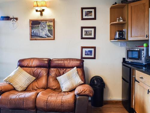 a brown leather couch sitting in a kitchen at Toms Cabin - Uk35173 in Elmsted
