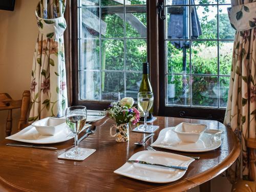 a wooden table with white plates and wine glasses at Toms Cabin - Uk35173 in Elmsted