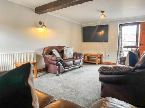a living room with leather furniture and a flat screen tv at Tom Wragg Suite - Uk40248 in Bakewell