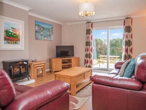 ein Wohnzimmer mit Sofa und Fernseher in der Unterkunft Puffin Cottage - Uk6731 in Lydstep