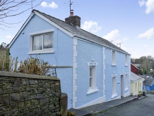 a blue house with white windows and a stone wall at Delfryn in Llanarth