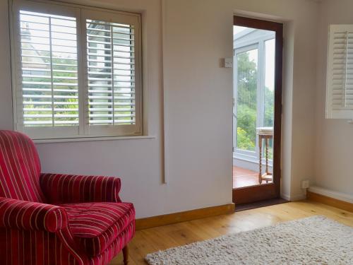 a living room with a red chair and a window at Eastwood Lodge in Bath