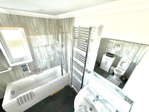 ein Badezimmer mit Badewanne, Waschbecken und Toilette in der Unterkunft Golf View Spacious Bungalow 2 Bathrooms, Free Parking WiFi in Elgin