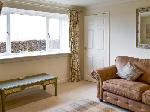 a living room with a couch and a window at Foulden Hill Farm Cottage in Foulden