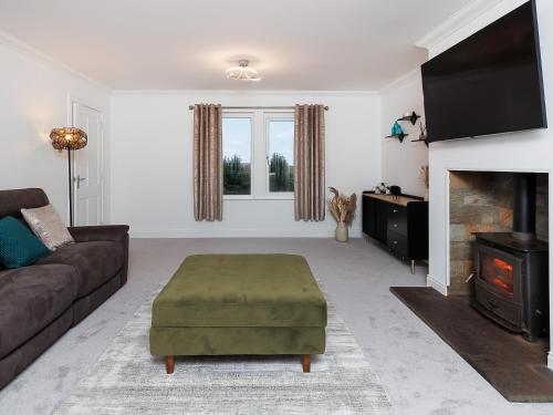 een woonkamer met een bank en een open haard bij Sealladh Na Mara in Pollachar