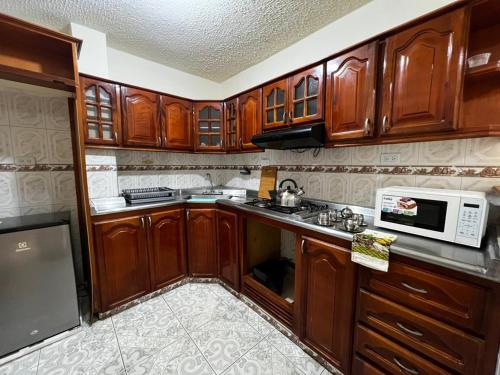 a kitchen with wooden cabinets and a microwave at Casa Rincón in Curití