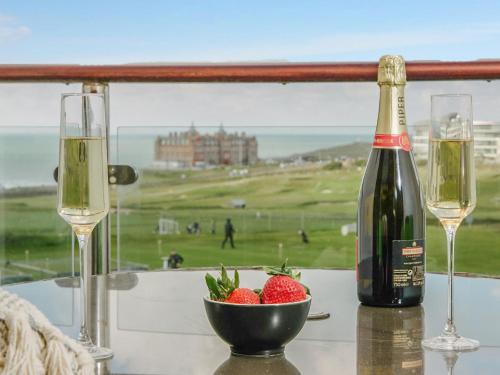 a bottle of wine and two glasses on a table with strawberries at 50 Bredon Court in Newquay