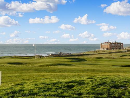 a view of a golf course with a castle and the ocean at 50 Bredon Court in Newquay