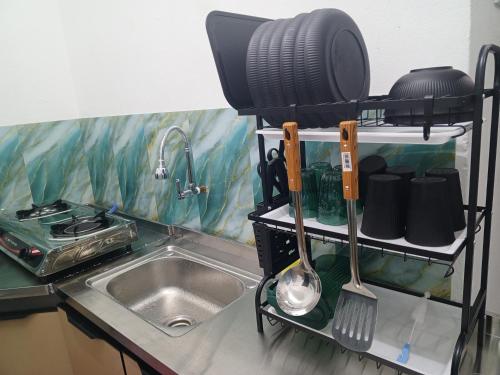 a kitchen counter with a sink and a shelf with utensils at Bae Homestay Taman Mega Alor Setar Wi-Fi Netflix 