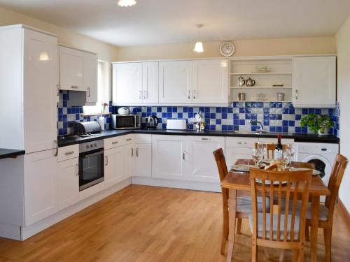 a kitchen with white cabinets and a table with chairs at Peace in Whauphill