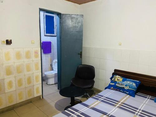 a bedroom with a bed and a chair and a toilet at Flat Hôtel Alpha in Kinshasa