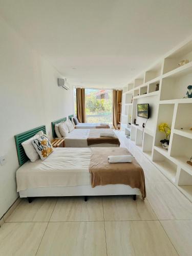 a bedroom with three beds and a window at Pousada MarÍsis Barra da Tijuca in Rio de Janeiro